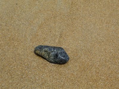 A single smooth stone balanced on another against a simple background.